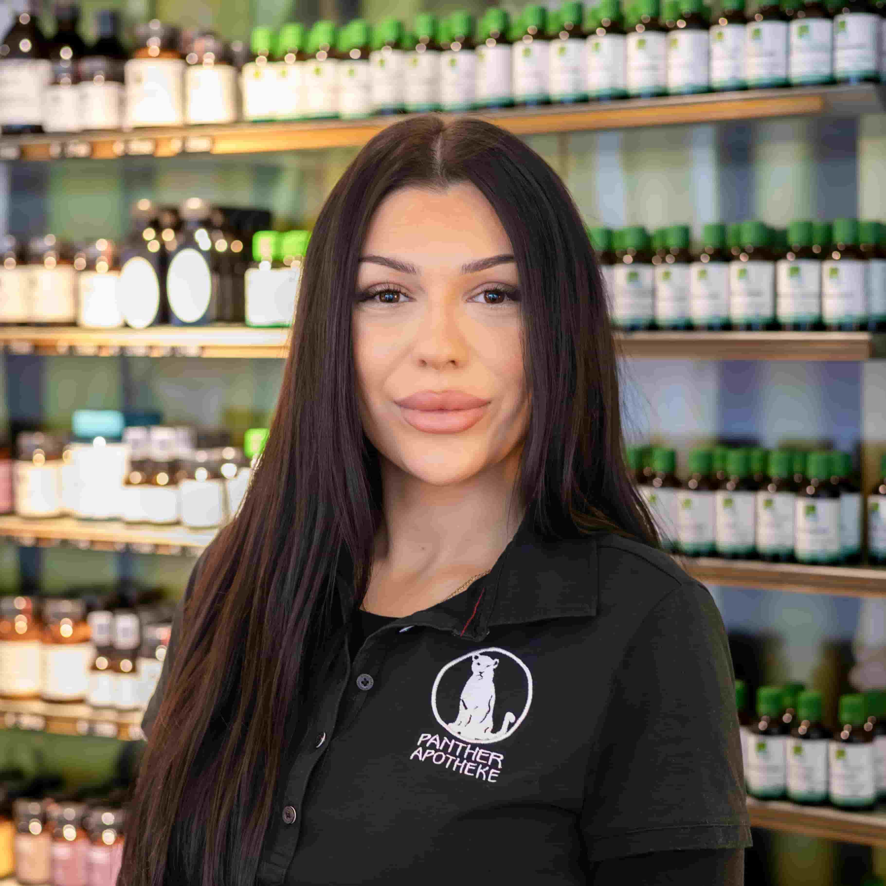 Porträt von Ardita Morina, stehend vor einem Produktregal.